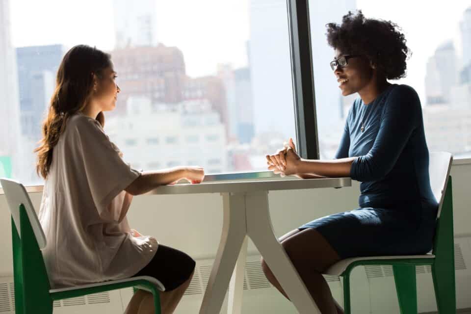 Two professionals discussing work together beside a laptop in an office