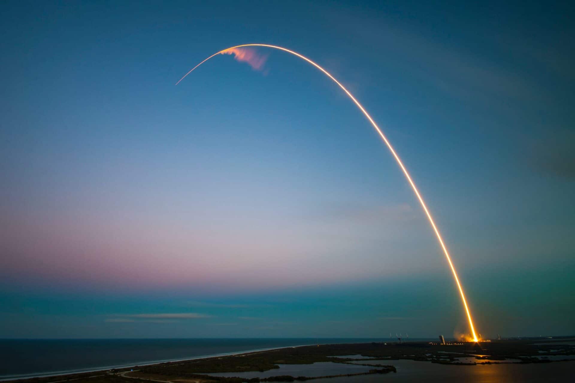 SpaceX rocket leaving a bright curved trail across the evening sky