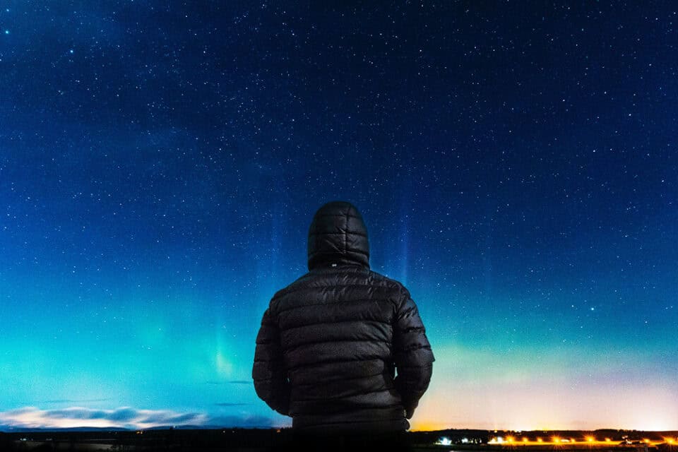 Lone figure beneath a clear night sky and distant stars