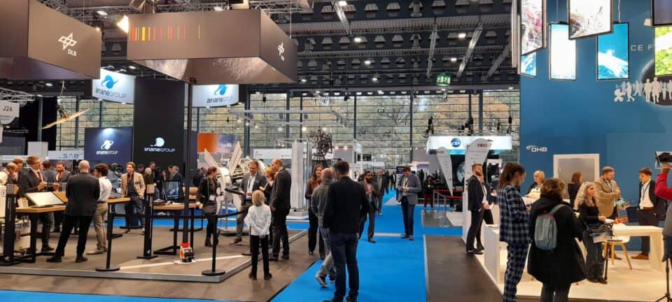 Visitors and exhibitors inside a busy space technology trade show hall