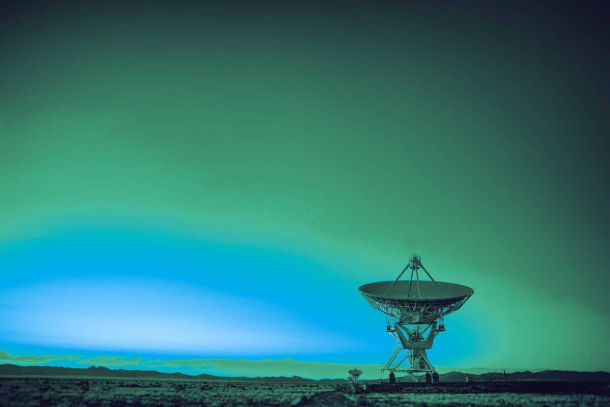 Satellite communications equipment beneath a bright green aurora