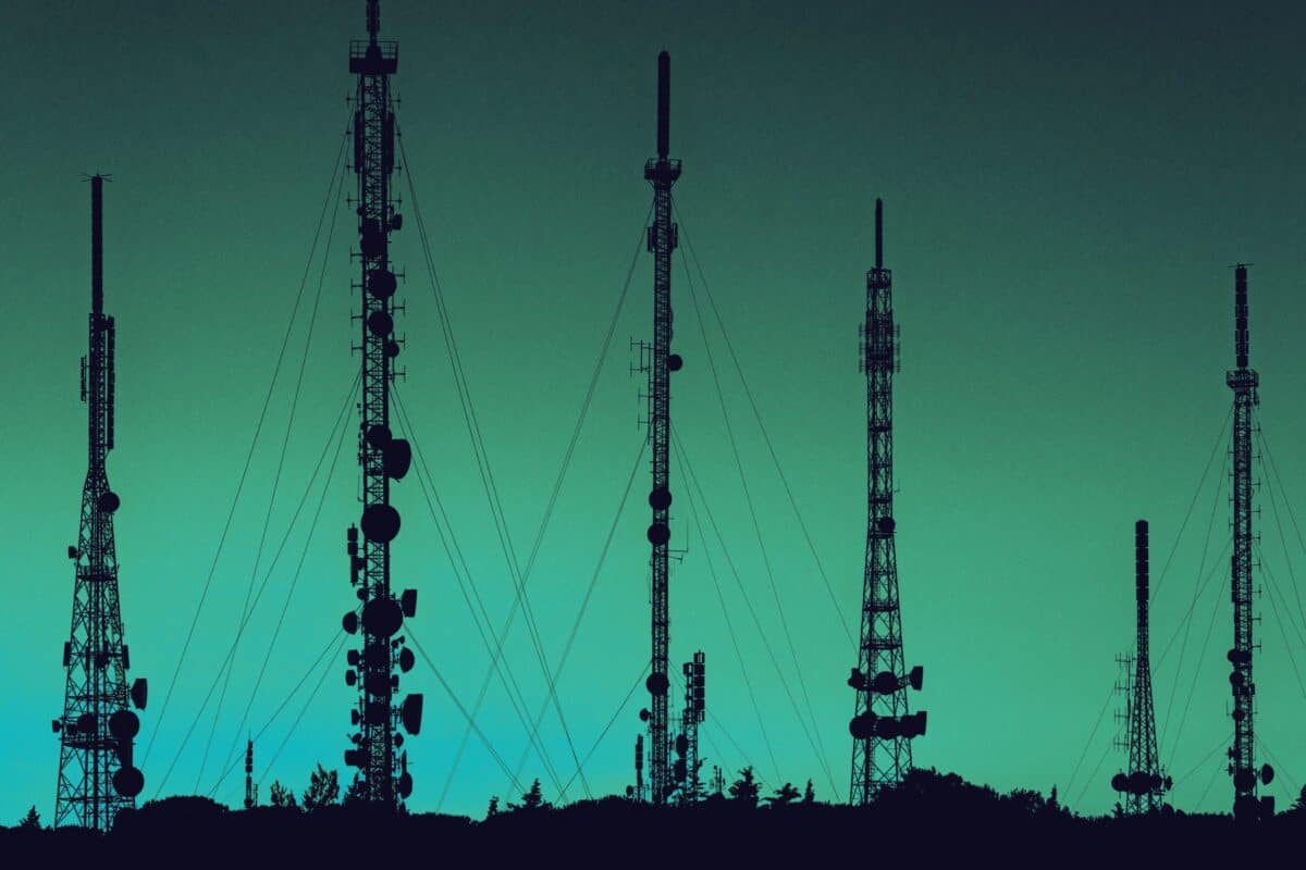 Multiple communications towers standing against a softly coloured sky