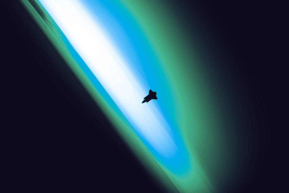 Satellite communications equipment beneath a bright green aurora