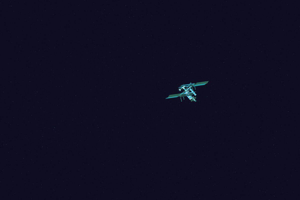 Small satellite travelling through dark space above Earth