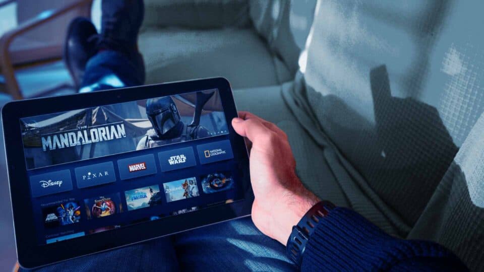 Person holding a tablet displaying a digital streaming interface