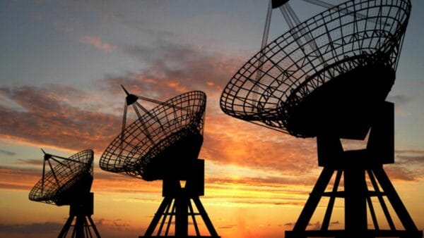 Satellite communications antennas silhouetted against a warm sky