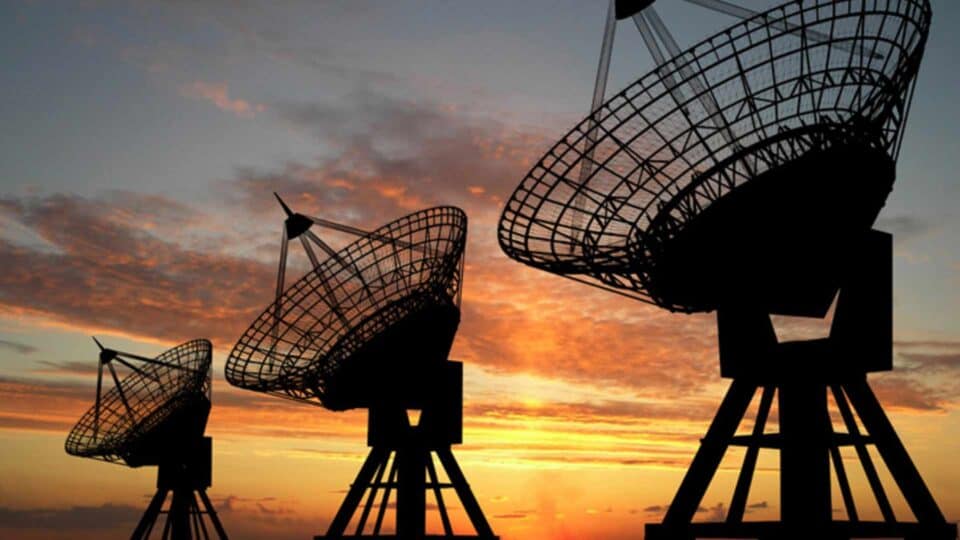 Satellite communications antennas silhouetted against a warm sky