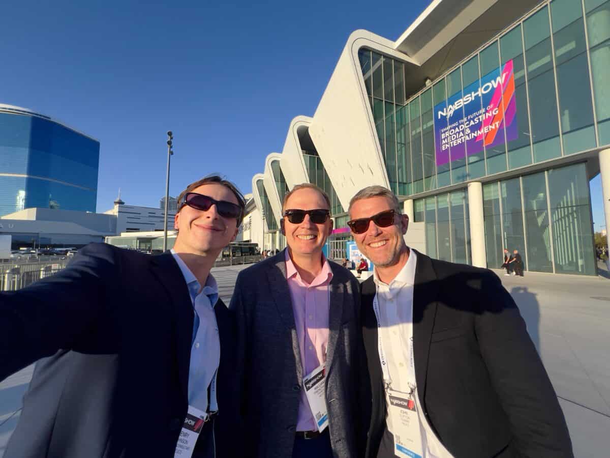 Three attendees posing together outside a space industry event