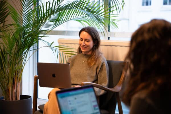 Professional smiling while working on a laptop in a bright office