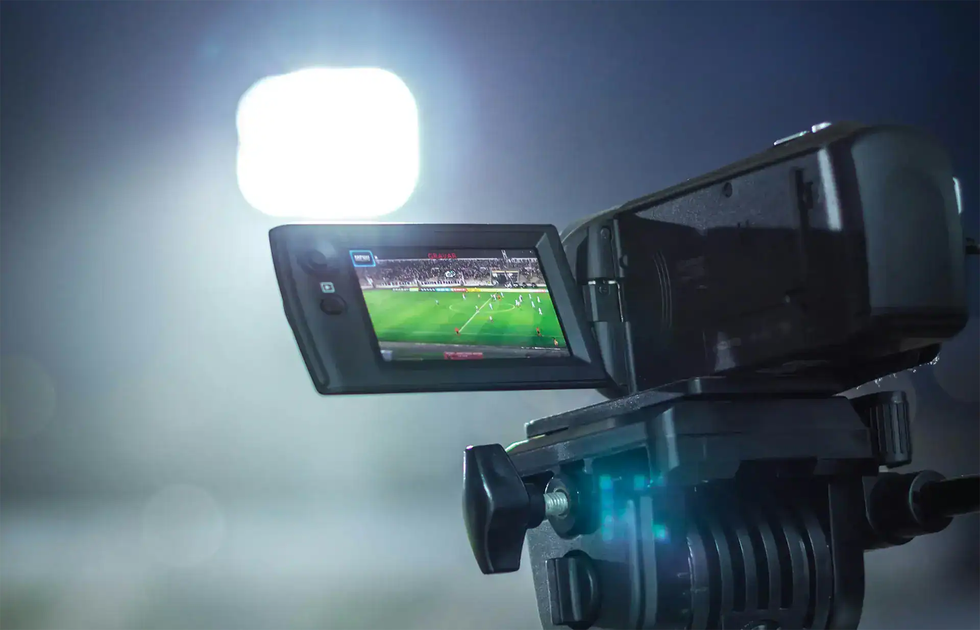 Video camera recording a live football match under studio lighting